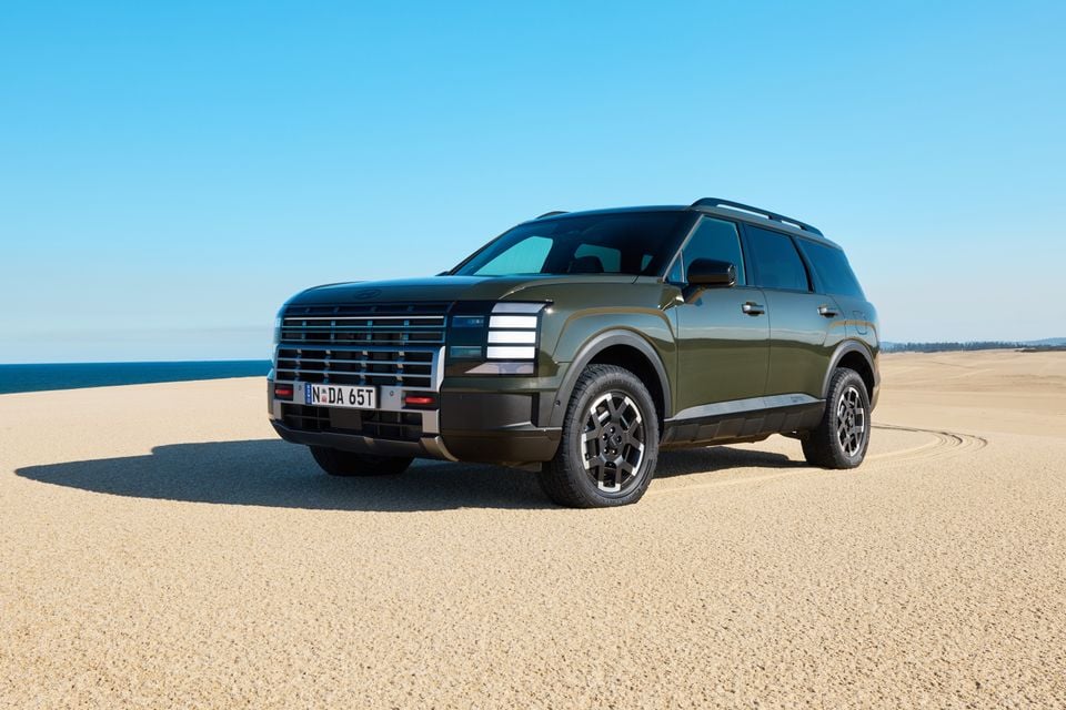 A dark green 2027 Hyundai Palisade XRT Pro large SUV seen from the front-side angle on a sandy coastal dune