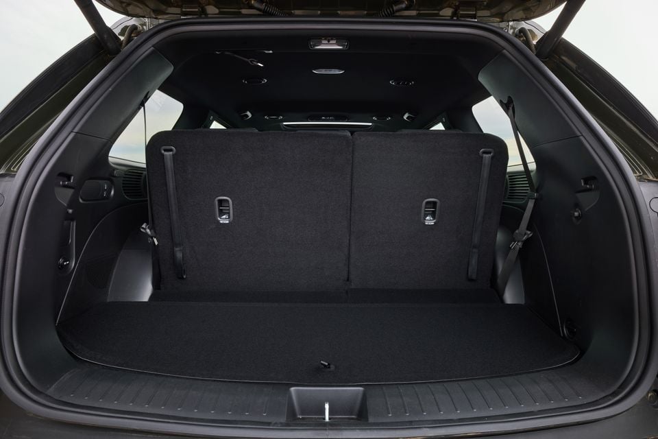 The empty boot of a 2027 Hyundai Palisade XRT Pro SUV, viewed from the rear with the tailgate open, showing a spacious, dark-carpeted cargo area with fold-down rear seat backs.