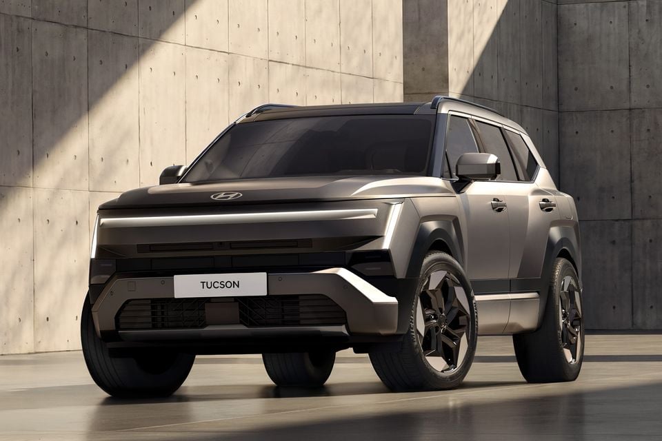 A grey 2027 Hyundai Tucson SUV seen from the front quarter view, parked indoors next to a concrete wall