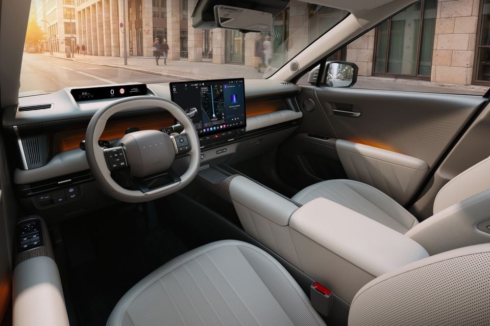 The interior of a 2027 Hyundai Tucson showing the steering wheel, dual digital screens and front seats in a light beige colour scheme