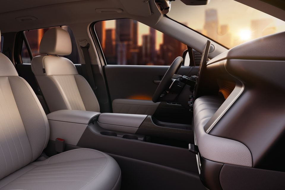 The interior of a 2027 Hyundai Tucson showing the front seats, steering wheel and dashboard with a city skyline visible through the windows.