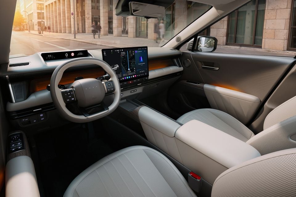 Interior of the 2027 Hyundai Tucson showing the dashboard, large infotainment touchscreen, digital instrument cluster, steering wheel, and light-coloured front seats