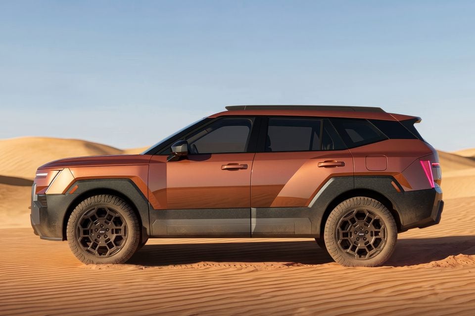 A copper-coloured 2027 Hyundai Tucson XRT Pro SUV photographed from the side on a desert sand dune.