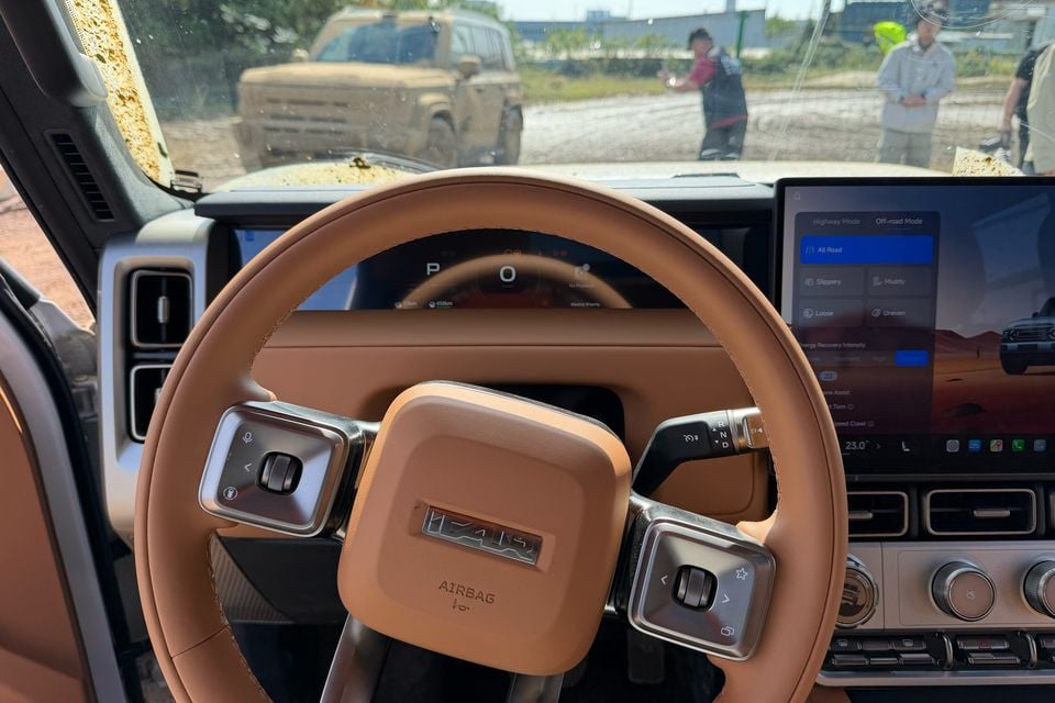 Volante bronzeado, display de instrumentos e controles do painel em um carro de teste iCaur V25 estrangeiro com volante à esquerda.
