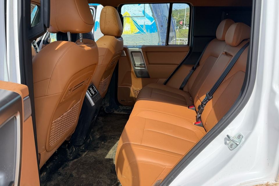 Banco traseiro castanho, apoios de cabeça e saídas de ventilação traseiras em um carro de teste iCaur V25 estrangeiro.