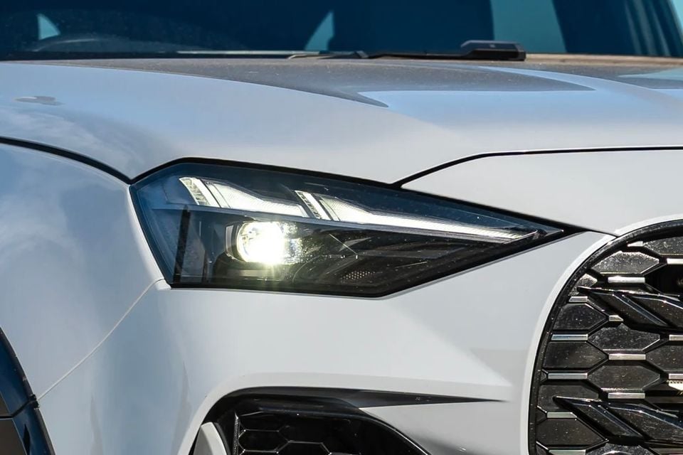 Close-up of the headlight and grille on a white 2027 Isuzu MU-X X-Terrain