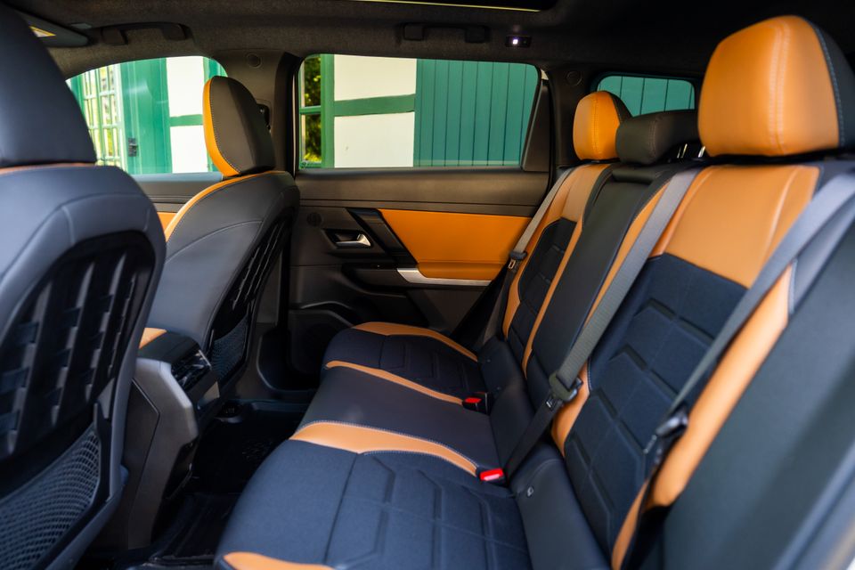 Rear interior of the 2027 Jeep Compass showing two-tone tan and dark blue rear seats with orange door panel accents