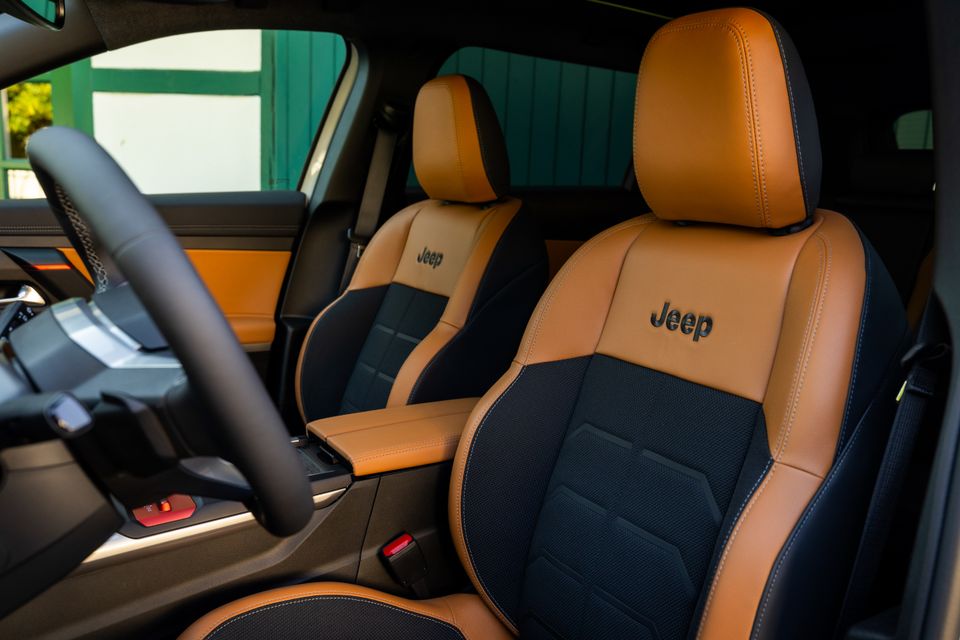 Jeep-branded two-tone tan leather and black fabric front seats inside a 2027 Jeep Compass, with the steering wheel visible on the left