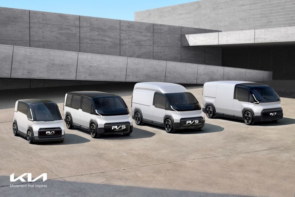 Kia PV1, PV5, PV5 High Roof, and PV7 electric concept vans lined up together in front of a modern concrete building