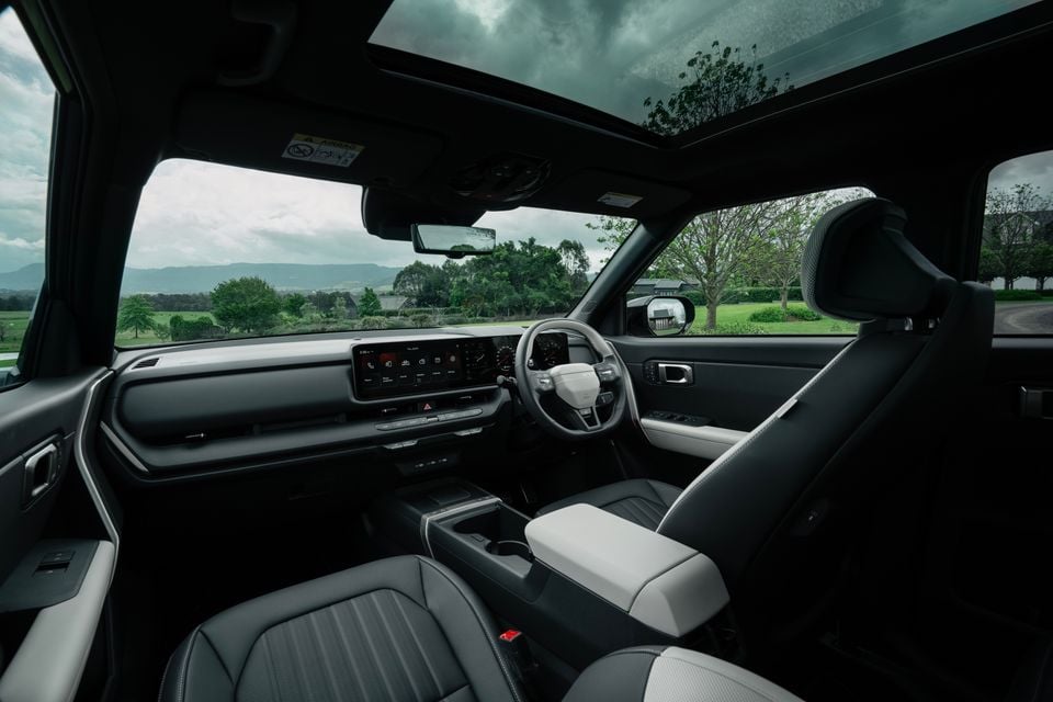 Dashboard, steering wheel and front seats of the 2027 Kia Seltos GT-Line hybrid, with a widescreen display and panoramic sunroof