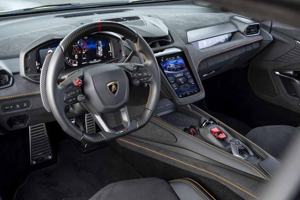 The interior of a 2027 Lamborghini Temerario, showing the steering wheel, digital instrument cluster, centre touchscreen and centre console with carbon fibre trim.