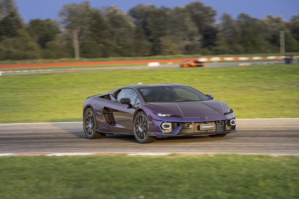A purple Lamborghini Temerario sports car driving on a race track, seen from the front quarter angle