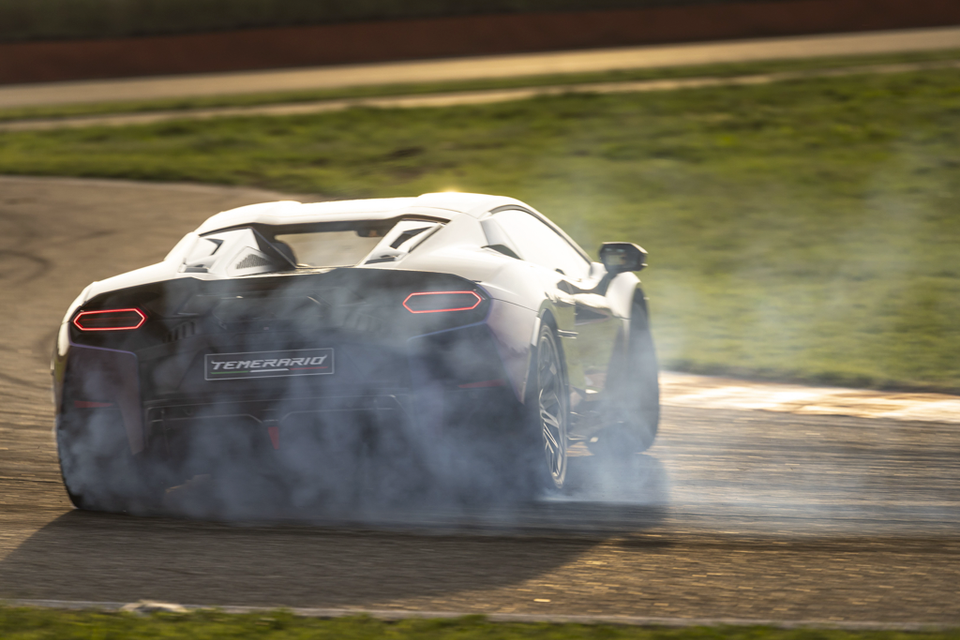 A Lamborghini Temerario sports car drifts on a racetrack with tyre smoke billowing behind it, seen from the rear