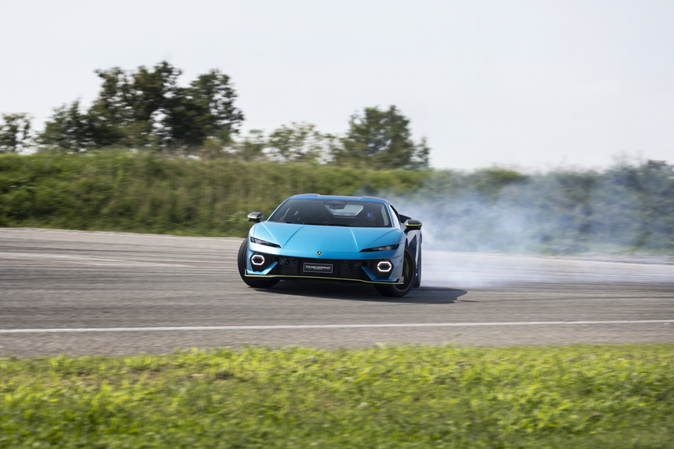 A blue Lamborghini Temerario supercar drifts on a race track with smoke coming from its rear tyres.