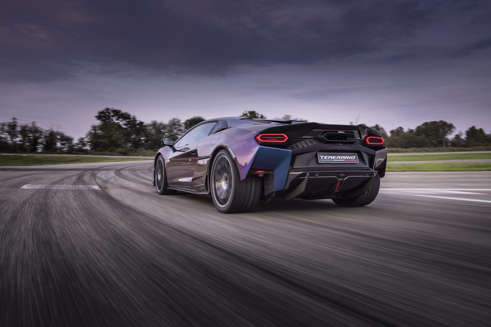 A purple Lamborghini Temerario sports car driving fast on a racetrack, seen from the rear quarter