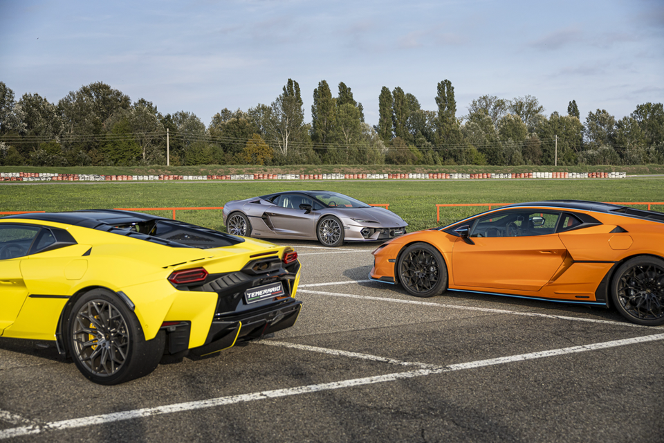Three Lamborghini Temerario sports cars in yellow, silver and orange parked on a track, with the yellow car shown from the rear and the others in profile