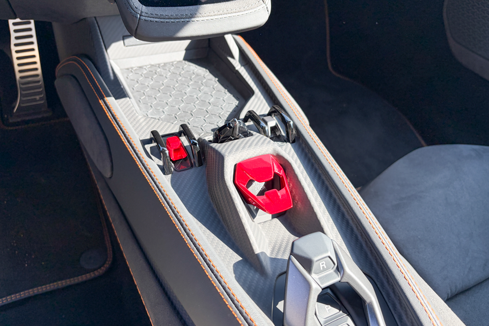 Close-up of the centre console in a Lamborghini Temerario, showing the red engine start-stop button and carbon-fibre trim.