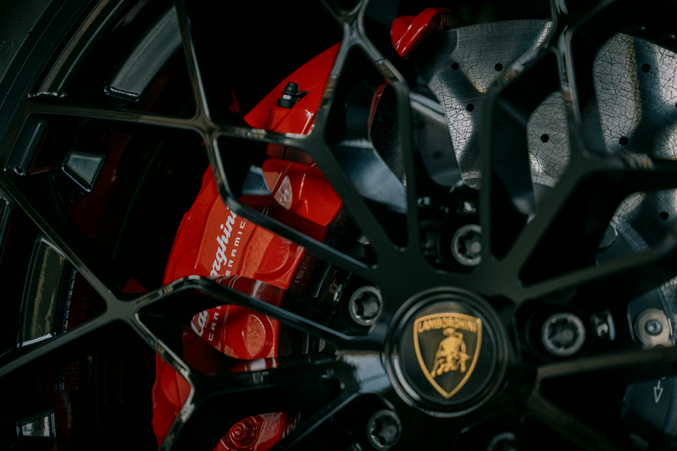 Close-up of a black alloy wheel on a 2027 Lamborghini Urus SE Performante, showing the gold Lamborghini centre cap, red carbon-ceramic brake caliper and drilled disc