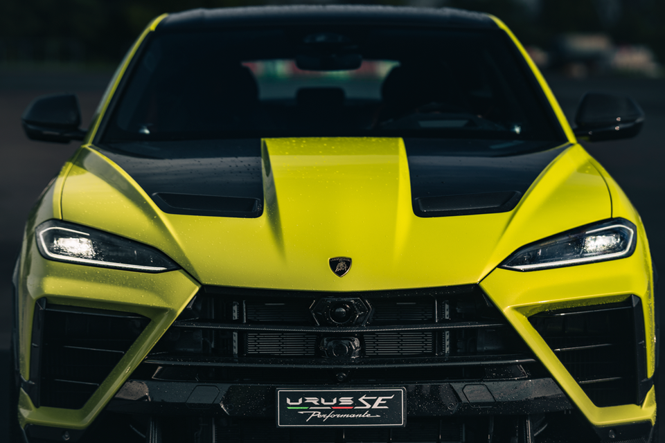 A yellow 2027 Lamborghini Urus SE Performante SUV seen head-on, with a black carbon-fibre bonnet, LED headlights and front grille.