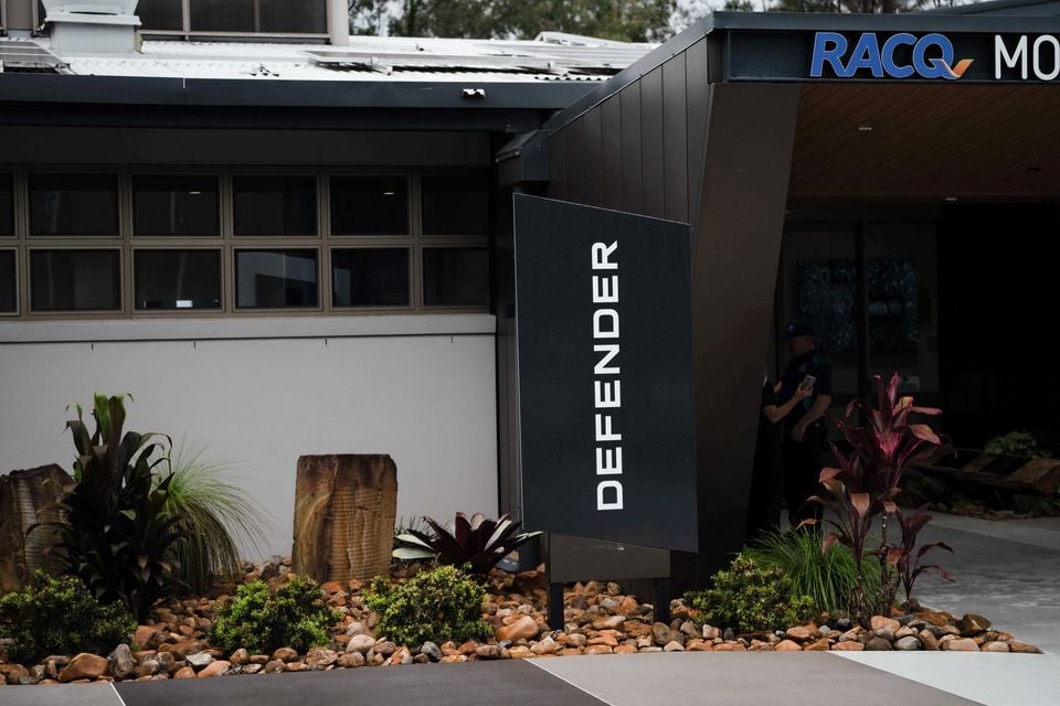 A Land Rover Defender branded sign outside an RACQ venue, surrounded by native Australian landscaping