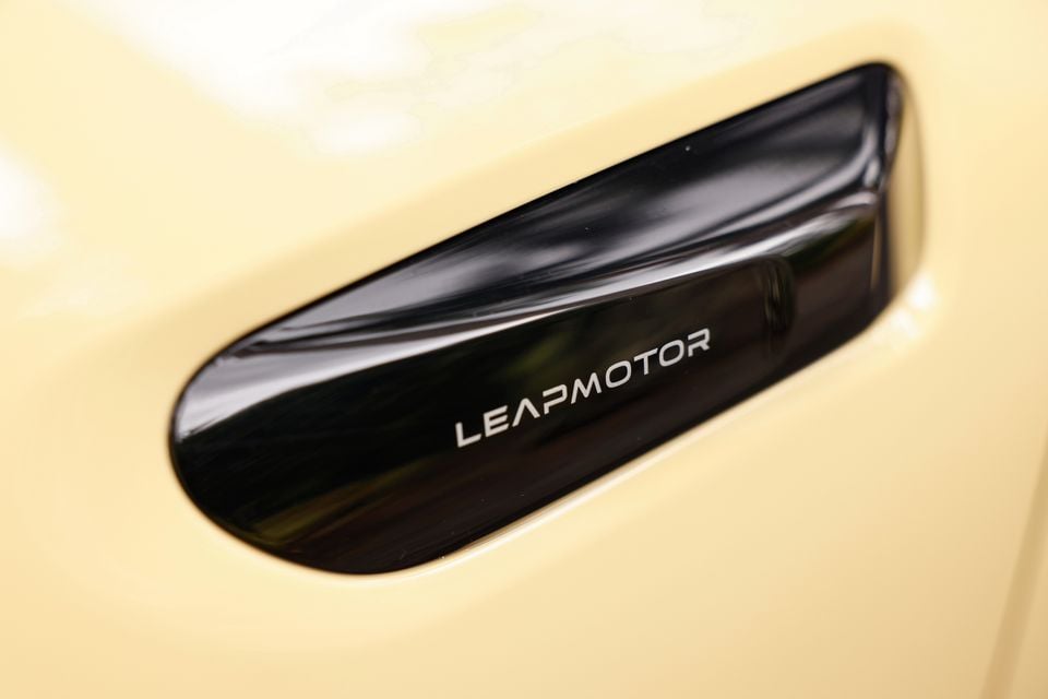 Close-up of a gloss black Leapmotor-branded door handle on the cream bodywork of a 2027 Leapmotor B05