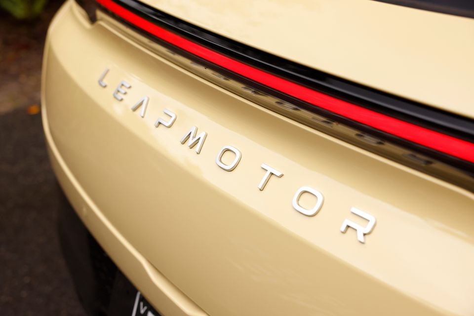 Close-up of the chrome Leapmotor lettering on the cream tailgate of a 2027 Leapmotor B05, beneath its full-width red tail-light bar