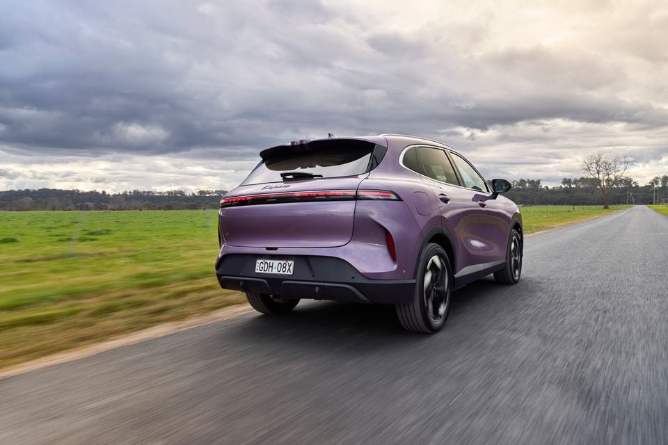 A purple Lepas L6 SUV seen from the rear while driving on a rural road under a cloudy sky