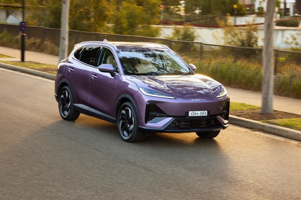 A purple Lepas L6 SUV driving on a suburban road, seen from the front-left side