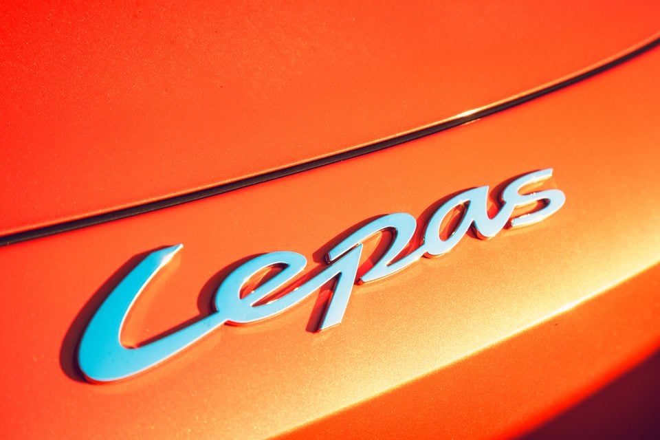 Close-up of the chrome Lepas script badge on the orange tailgate of a 2027 Lepas L6 Signature electric SUV