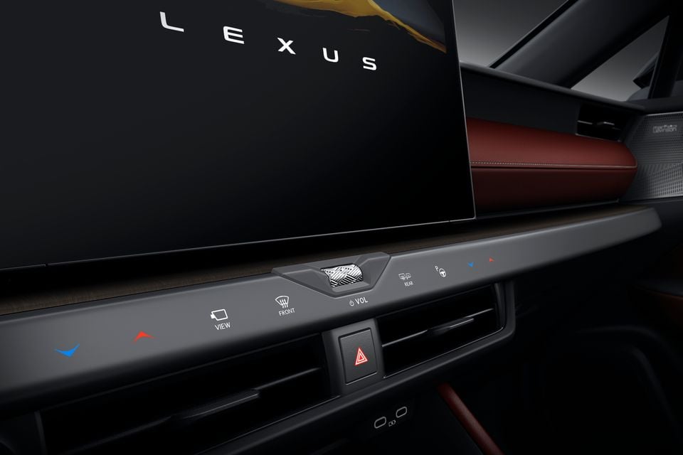 The Lexus infotainment touchscreen and centre console controls of the 2027 Lexus NX facelift, showing the Lexus logo on the display alongside climate and audio controls