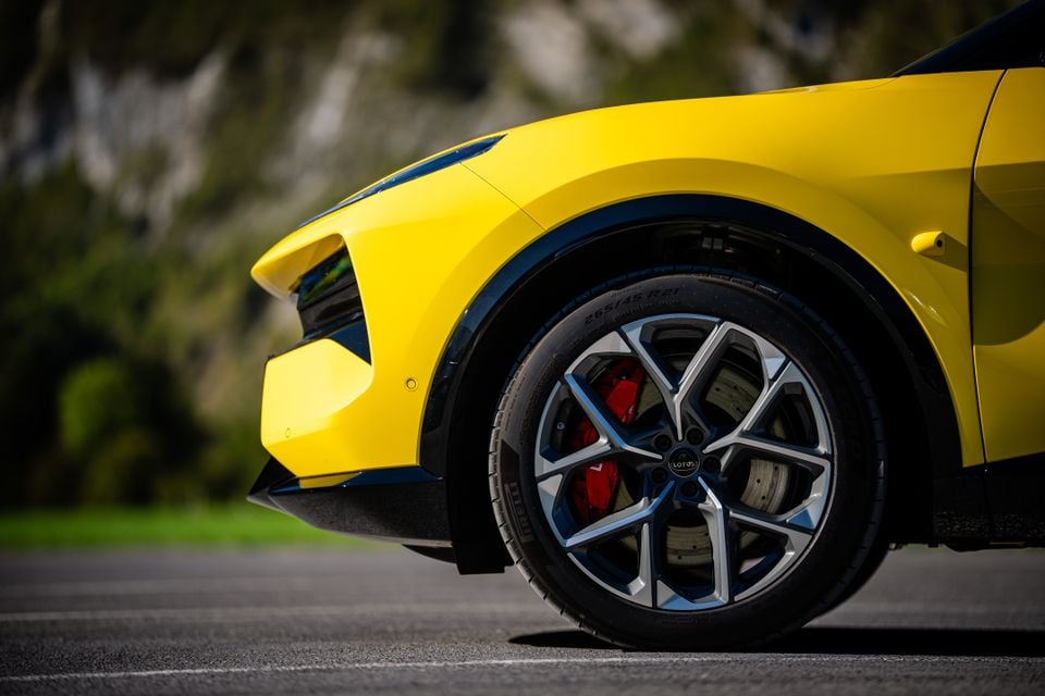 Close-up of the front wheel of a yellow 2027 Lotus Eletre X, showing a two-tone alloy wheel, red brake caliper and front bumper