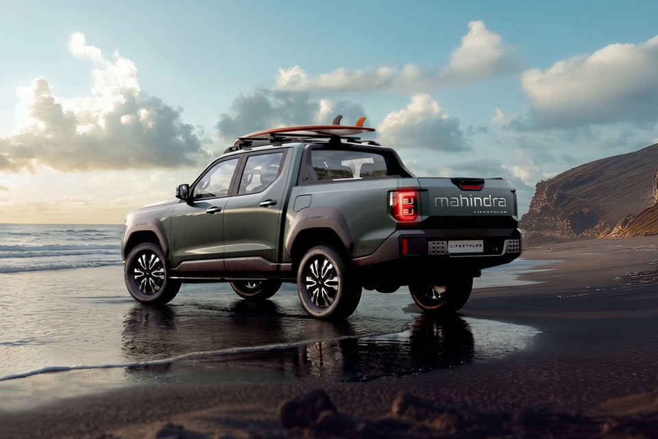 Mahindra Lifestyler dual-cab ute concept seen from the rear three-quarter angle on a beach, finished in olive green with a surfboard on the roof rack