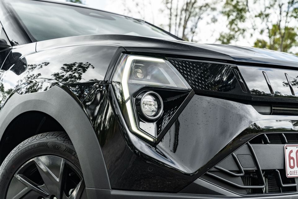 Close-up of the front headlight and fog light assembly on a black Mahindra XUV 3XO, showing LED daytime running lights and angular bodywork styling