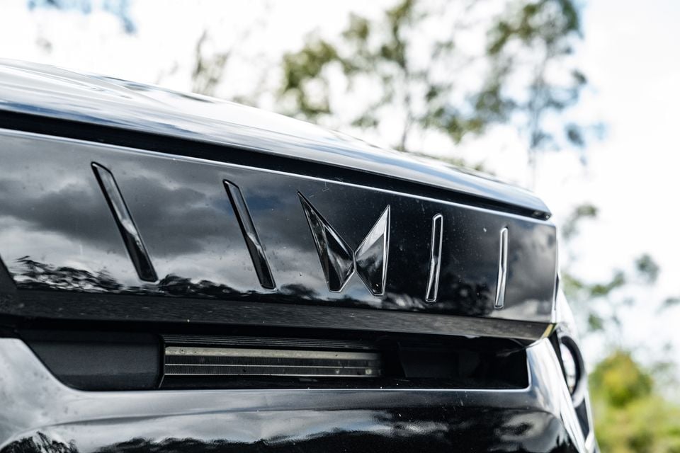 Close-up of the Mahindra logo and decorative trim panel on the rear of a black Mahindra XUV 3XO