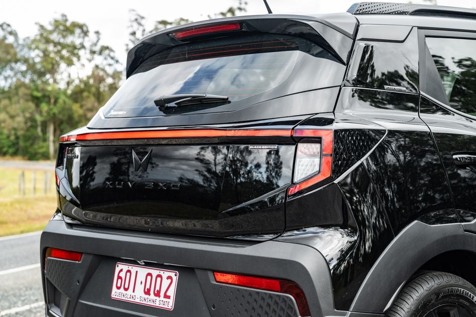Rear of a black Mahindra XUV 3XO Black Edition SUV with a Queensland number plate, parked on a road surrounded by trees