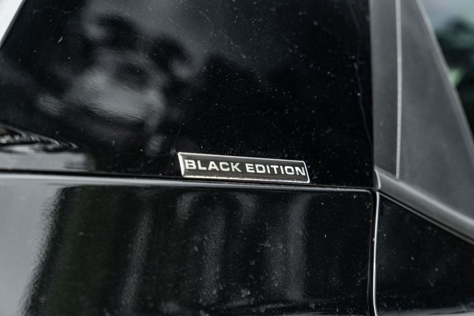 Close-up of a 'Black Edition' badge on the rear quarter panel of a Mahindra XUV 3XO Black Edition, shown wet with rain droplets