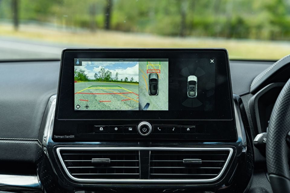 The touchscreen infotainment display in a Mahindra XUV 3XO showing the reversing camera feed with parking guidelines alongside a 360-degree surround view and proximity sensor display