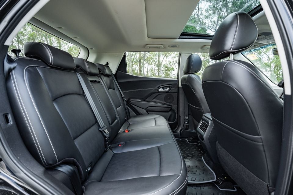 Rear passenger seats of the Mahindra XUV 3XO interior, showing black leather upholstery with white contrast stitching, a panoramic sunroof, and rear air vents