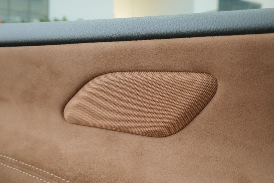 Close-up of a speaker grille set into the tan suede door trim of a 2027 Mazda 6e Atenza.