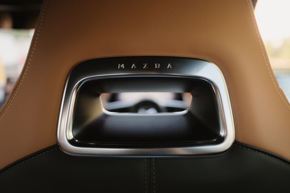 A close-up of a tan leather headrest with a Mazda-branded handle, likely from a 2027 Mazda 6e Atenza