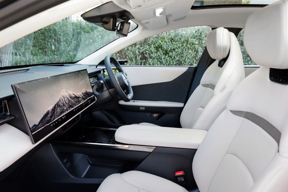 The white leather interior of a 2027 Mazda CX-6e shows the front seats, steering wheel and large portrait touchscreen infotainment display.