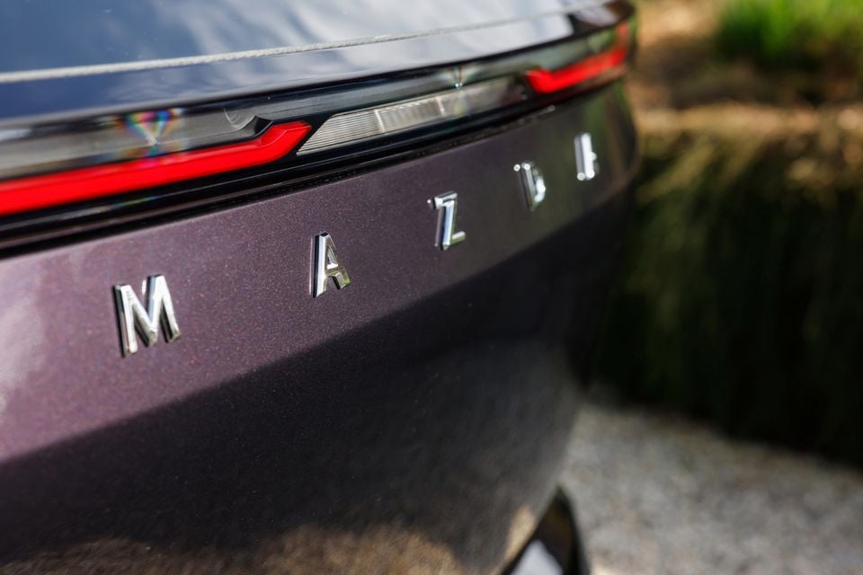 Close-up of the Mazda badge and tail light on the rear of a purple 2027 Mazda CX-6e