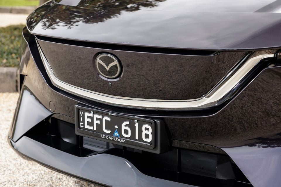 Close-up of the front grille and Mazda badge on a dark-coloured 2027 Mazda CX-6e electric SUV, with the Victorian number plate visible.