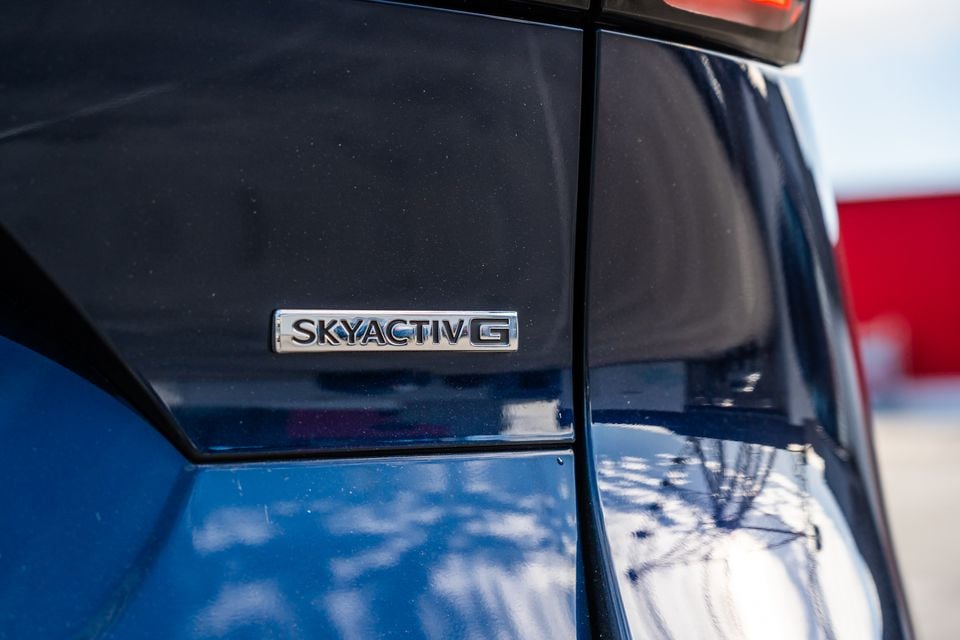 Close-up of the Skyactiv-G engine badge on a blue Mazda's rear pillar