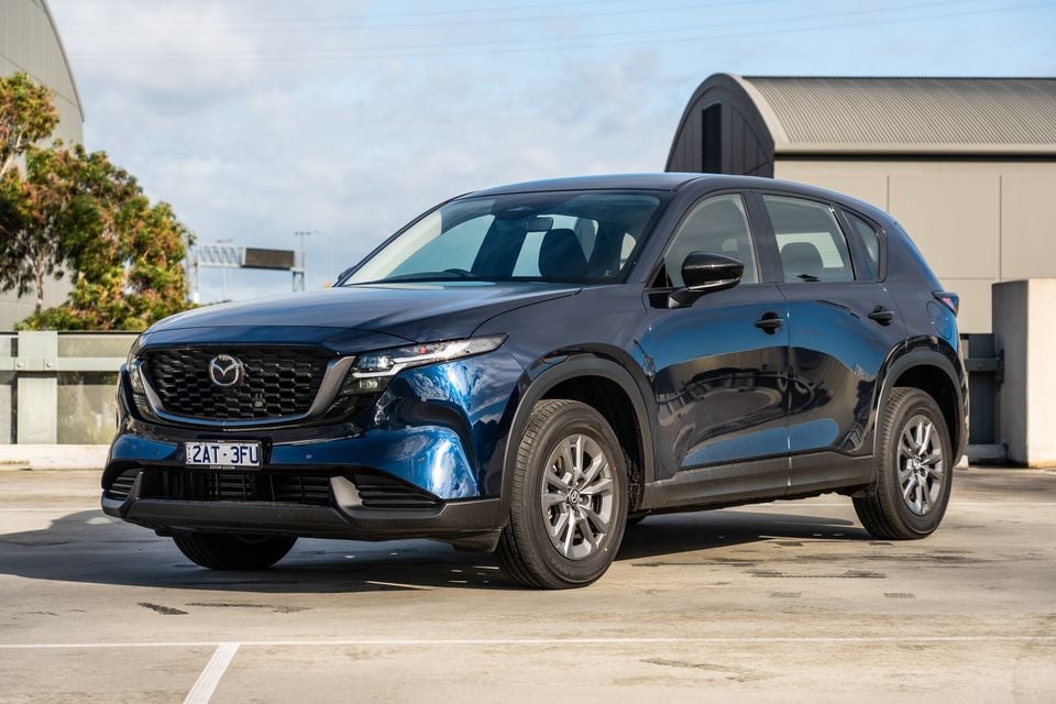 A dark blue Mazda CX-5 SUV seen from the front-left side, parked in an open car park