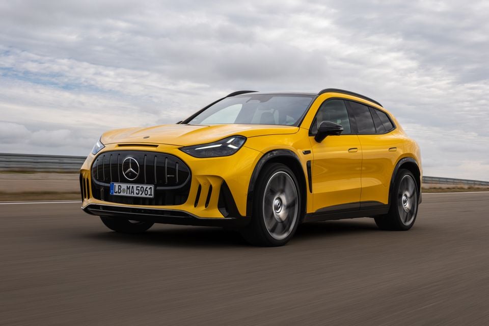A yellow 2027 Mercedes-AMG GT 63 SUV driving on a test track, seen from the front left