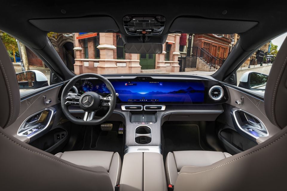 Interior of the 2027 Mercedes-Benz C-Class electric showing the steering wheel, wide dashboard screens, centre console and light grey front seats