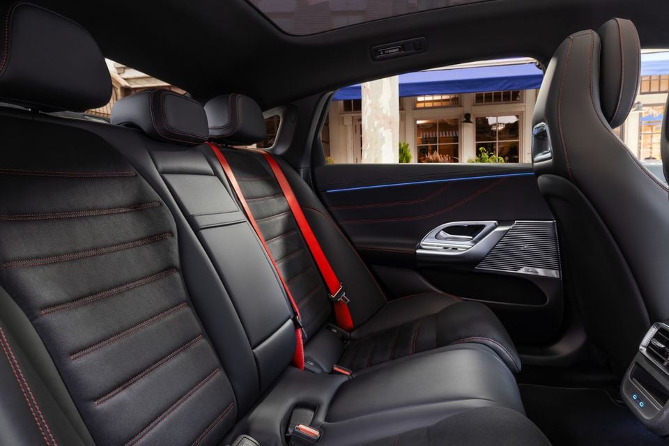 Rear seats of the 2027 Mercedes-Benz C-Class electric, trimmed in black with red stitching and red seatbelts, with a Burmester door speaker