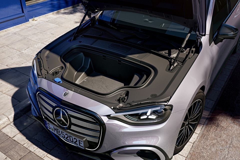 Um Mercedes-Benz Classe C Electric 2027 prateado com o capô levantado, revelando um compartimento de armazenamento dianteiro, visto de cima da frente