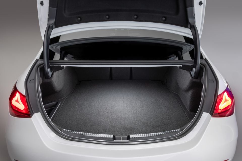Open boot of a white Mercedes-Benz C-Class sedan showing a spacious, carpeted cargo area with the lid raised